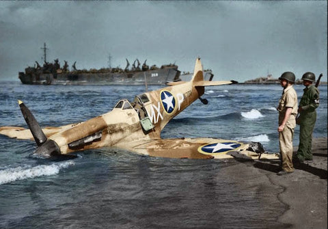 Wrecked military airplane on a beach with soldiers nearby, likely during World War II.